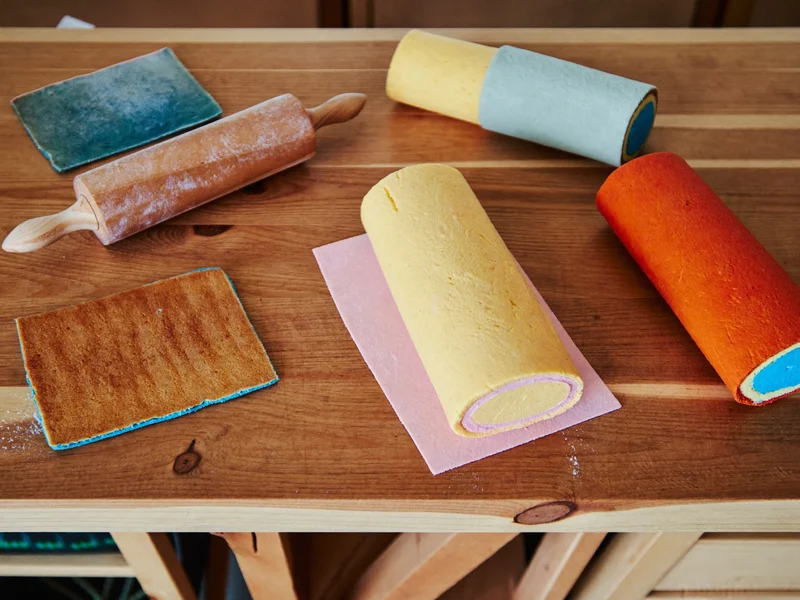Illustrative rolled fondant slabs in saturated colours beside a wooden rolling pin